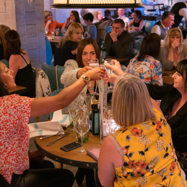 A group of people clinking glasses in Riva Blu Liverpool